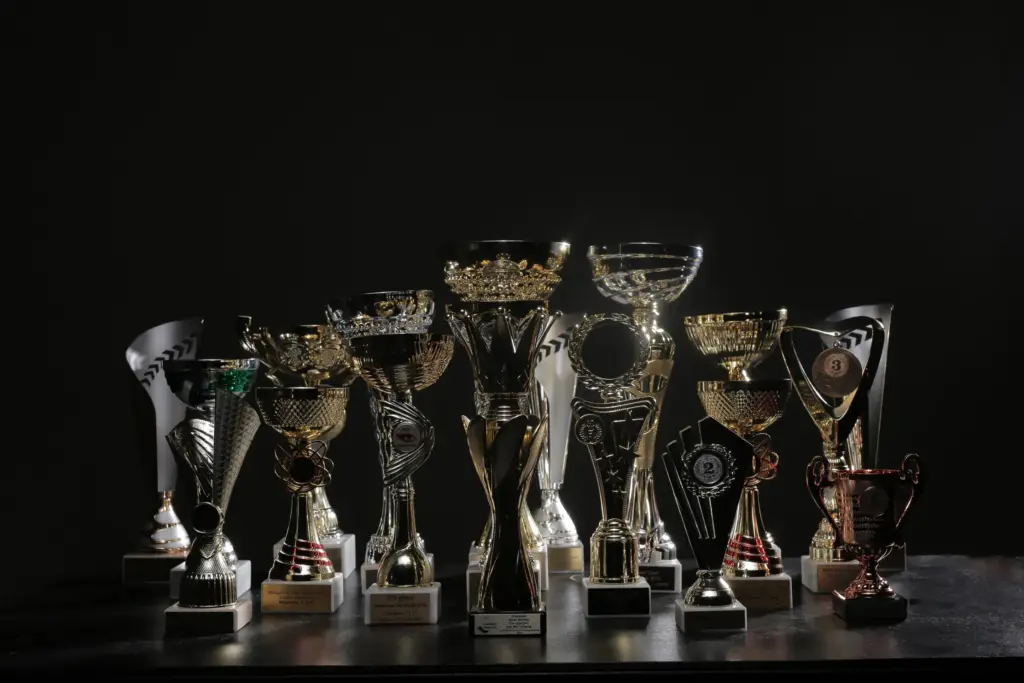 A row of gold and silver competition trophies displayed on a table against a black background.