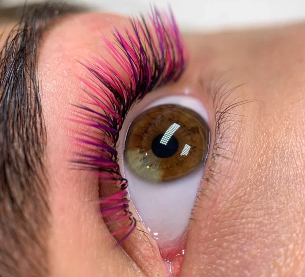 Close-up of a brown eye with dramatic black, pink, and purple lash extensions.