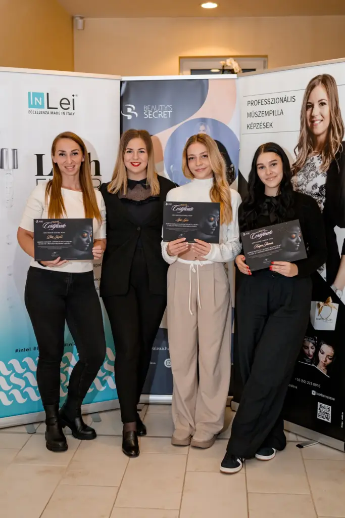 Four women pose with lash training certificates in front of Beauty’s Secret and InLei banners.