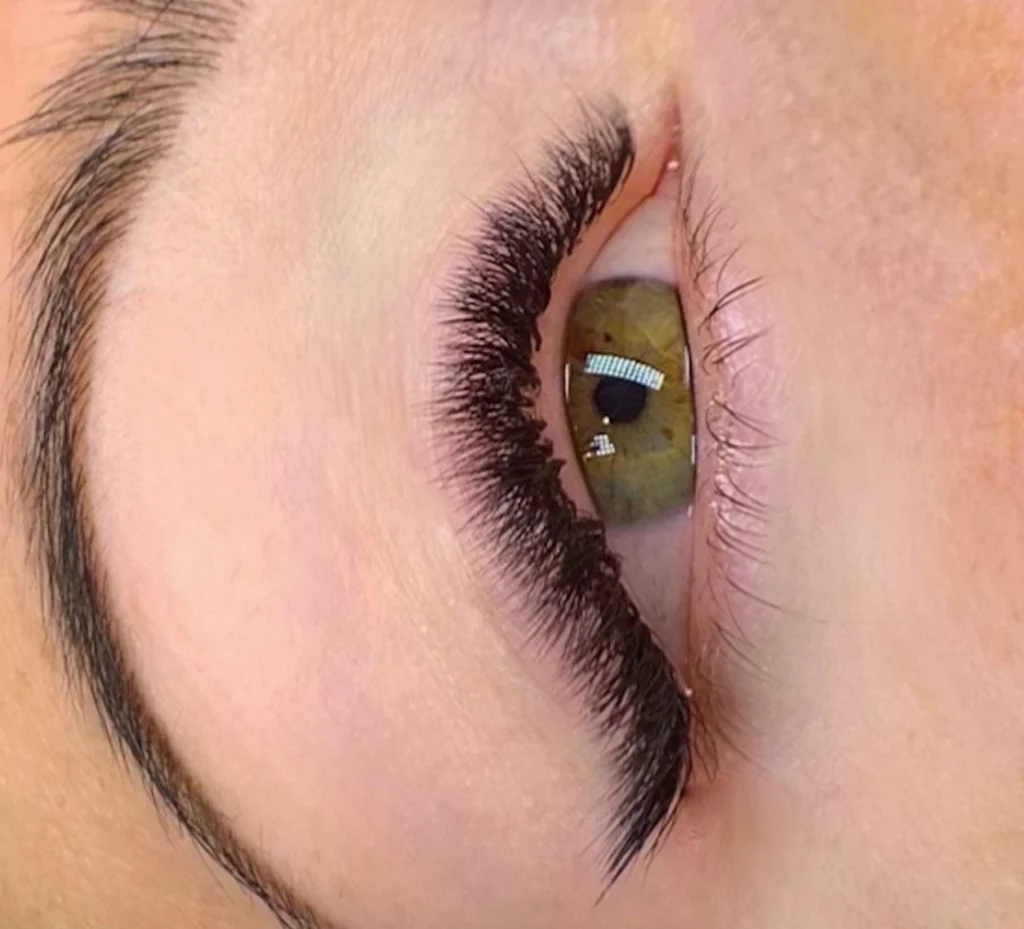 Close-up of a hazel eye with voluminous black lash extensions and a shaped eyebrow