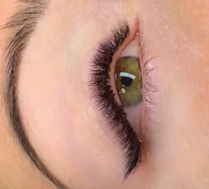 Close-up of a hazel eye with voluminous black lash extensions and a shaped eyebrow