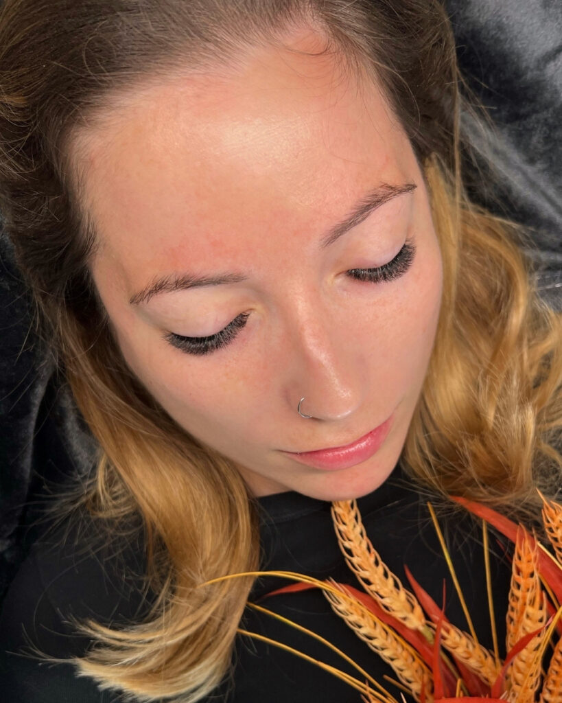 Woman with closed eyes showing long lash extensions and neatly shaped brows