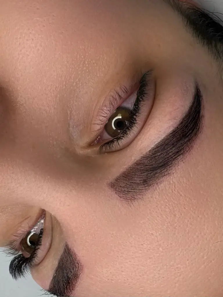 Close-up of shaped dark eyebrows and long curled lashes framing brown eyes