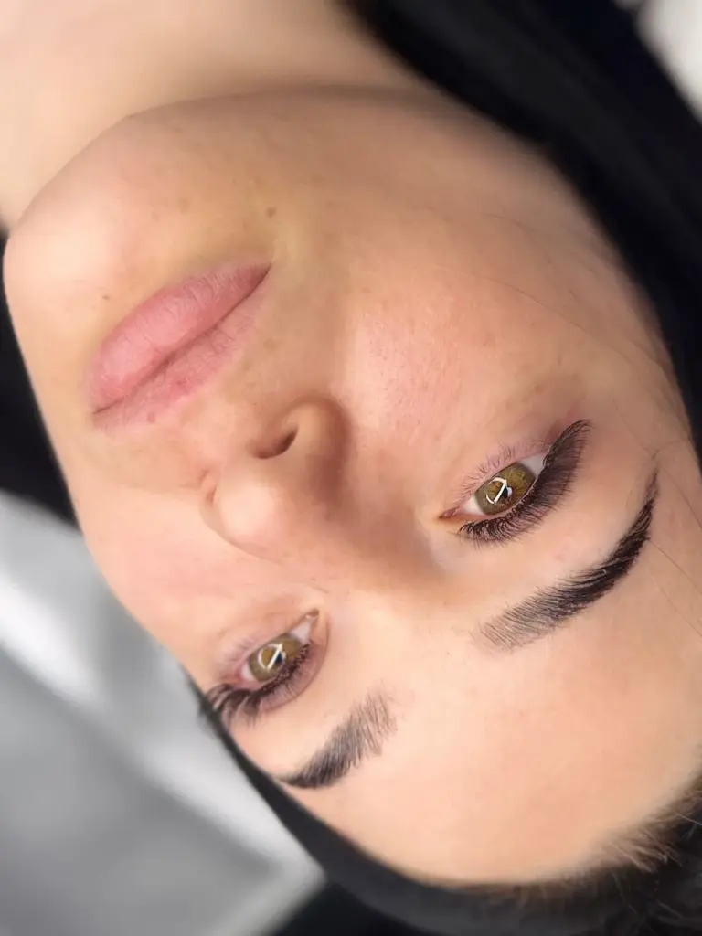 Close-up of a woman showcasing sculpted brows and long, curled eyelash extensions.