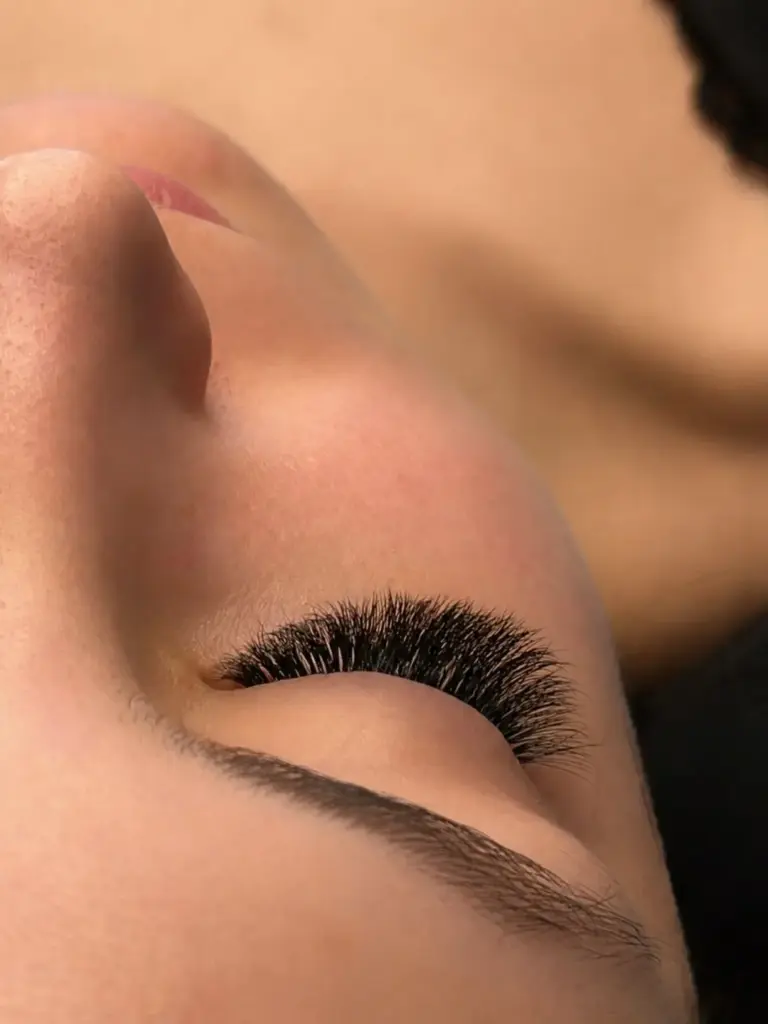Close-up of a closed eye with dense black lash extensions and a neatly shaped eyebrow.