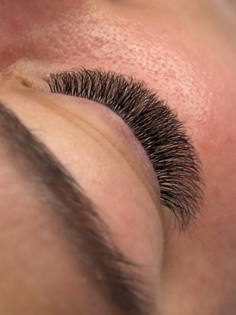 Close-up of a closed eye with long, dense black eyelash extensions fanned along the eyelid.
