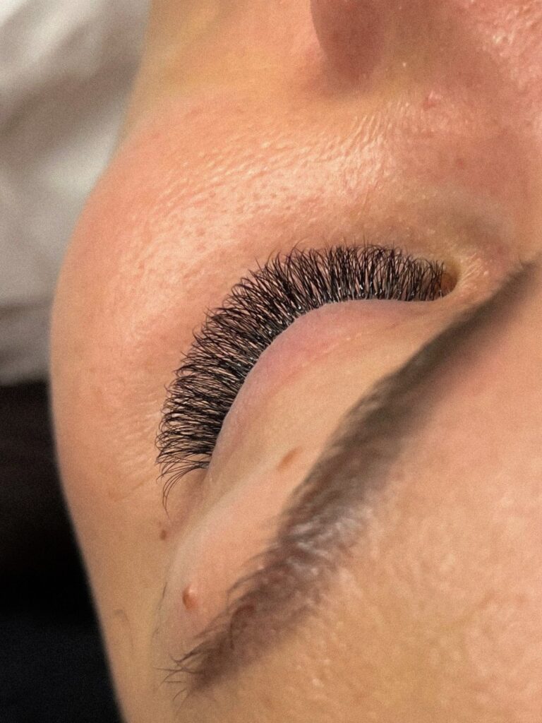 Close-up of a closed eye with dense, curled black eyelash extensions.