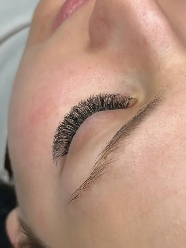 Close-up of a closed eye with voluminous dark lash extensions and a neatly shaped eyebrow.