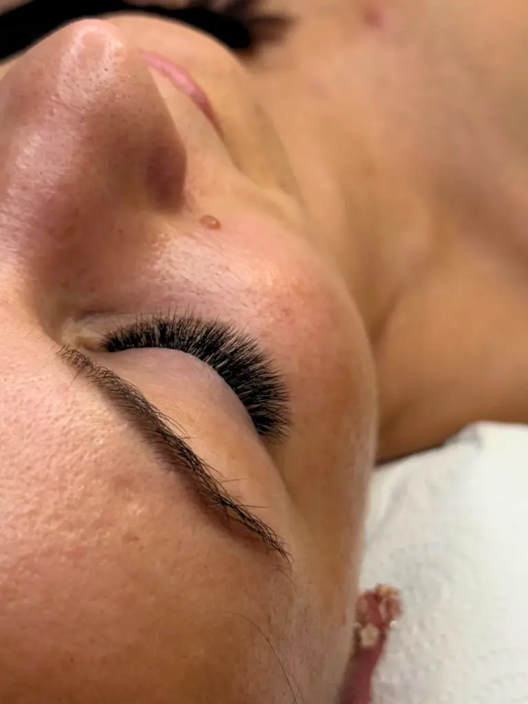Close-up of a closed eye with voluminous black lash extensions and a natural brow.