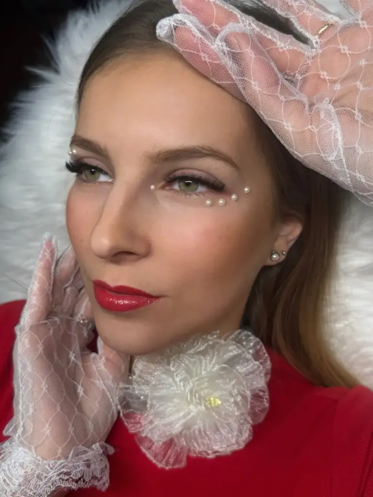 Model with dramatic false lashes, pearl accents, red lipstick, and lace gloves and collar