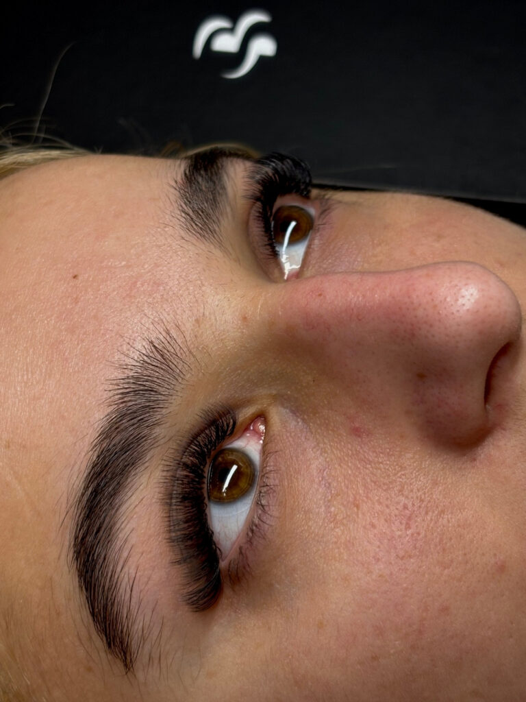 Close-up of a model with full, shaped brows and long, curled lash extensions.