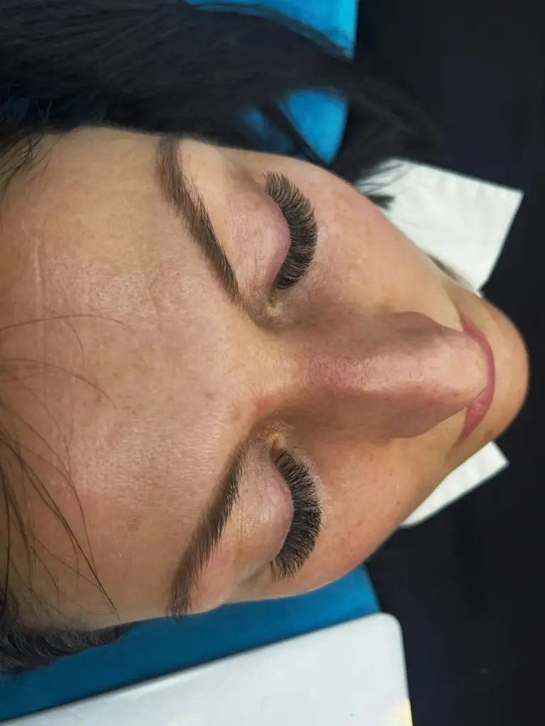 Close-up of a reclining woman with eyes closed, full eyelash extensions and shaped brows